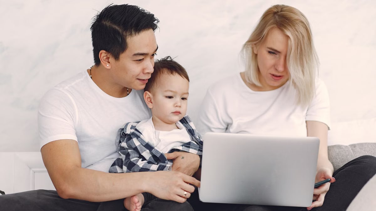 Young family enjoying quality time together, engaging with a laptop indoors.